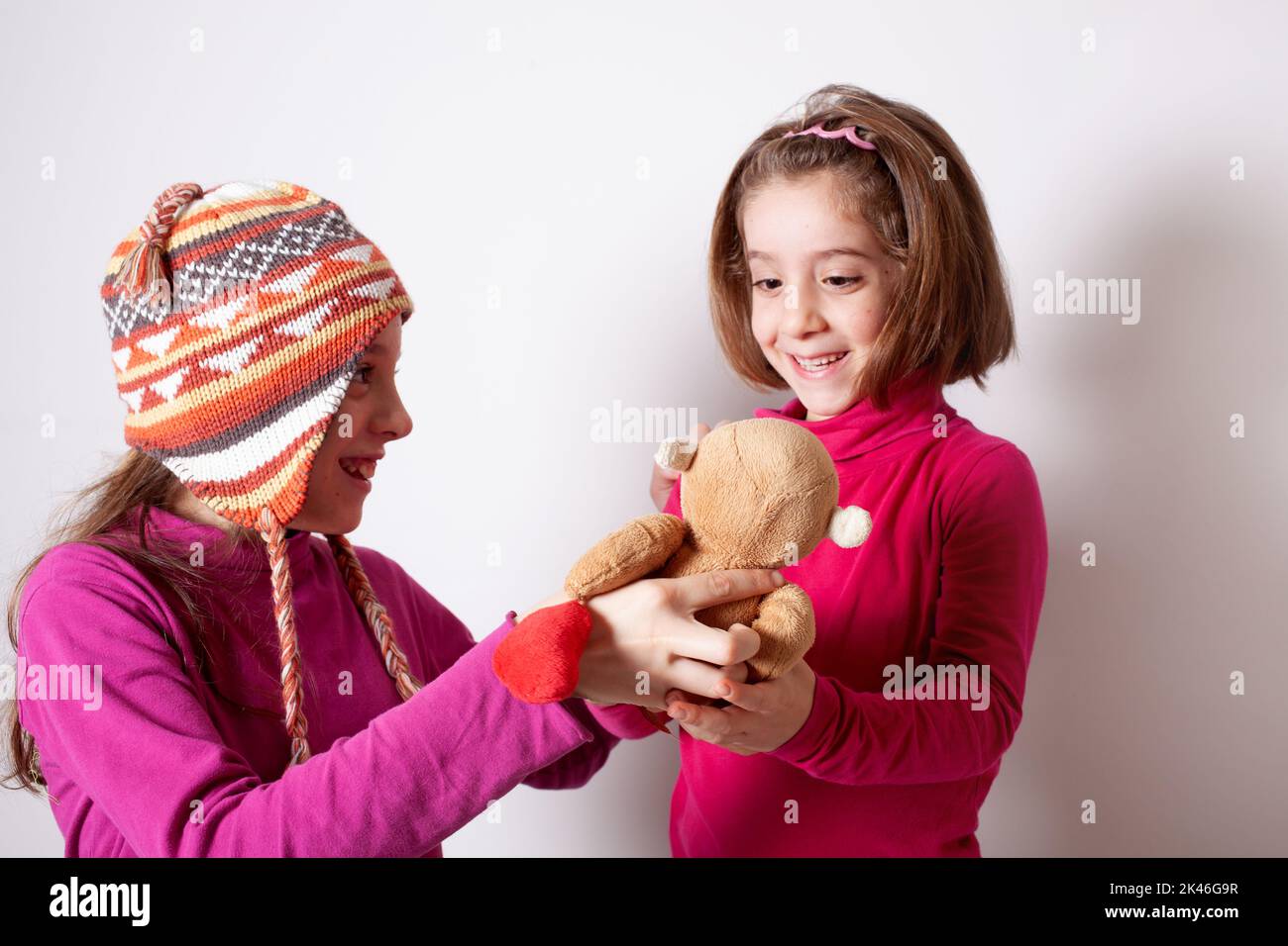 Petite fille donnant son jouet d'ours en peluche à sa sœur plus jeune. Mignonne fille donnant un cadeau à sa sœur. Enfant fille partageant un jouet avec un ami Banque D'Images