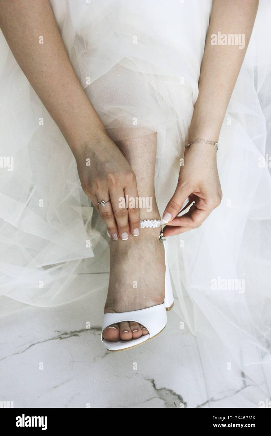 Mariée dans la robe de mariage mettant sur les chaussures de mariage, mariée se préparer pour le mariage, mode concept Banque D'Images