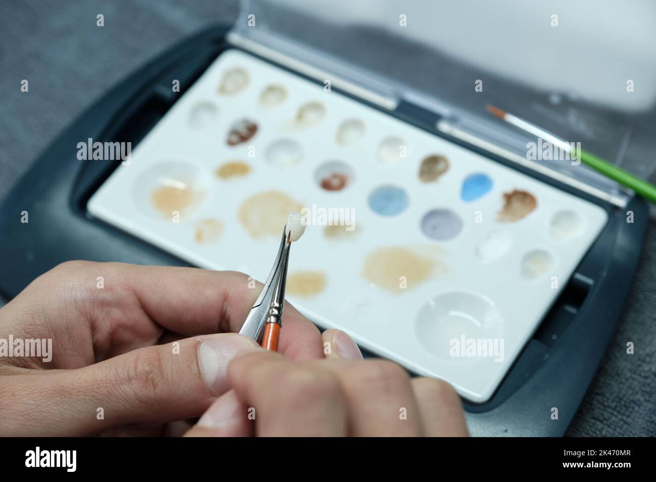 Un technicien dentaire ajoute du glaçage et de l'ombrage à un ensemble de fausses dents, au laboratoire. Coloration esthétique des dents. Concept de production d'implantates. Banque D'Images