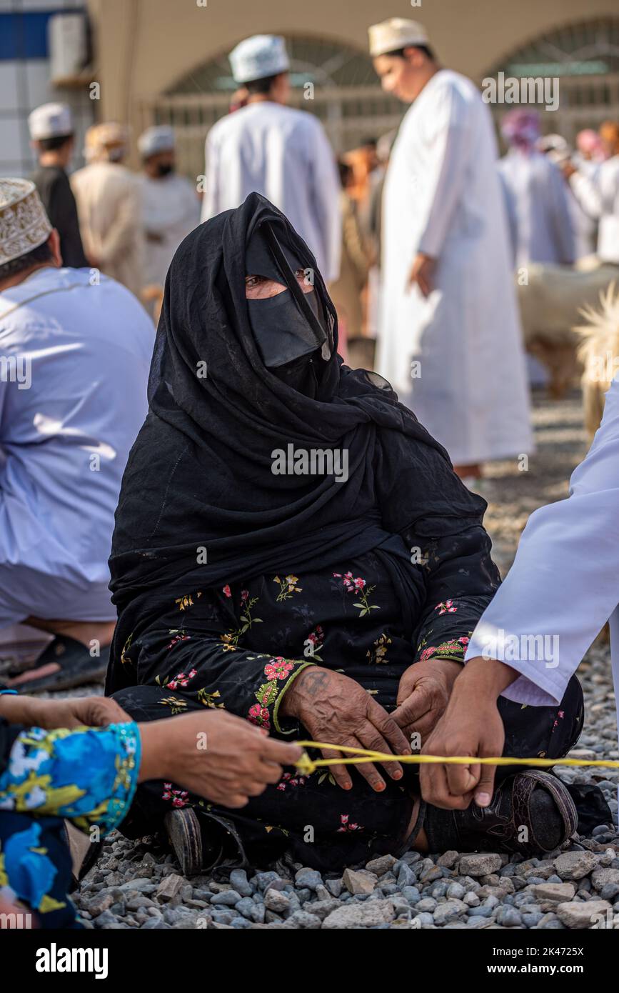 Femme avec 'battoulah' noir (masque facial) au marché du bétail vendredi matin, Nizwa, Oman Banque D'Images