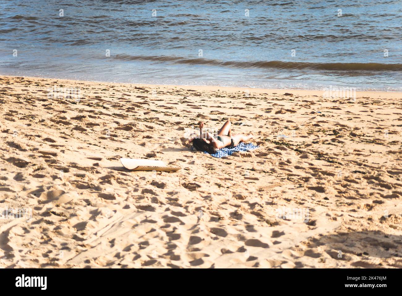 Salvador, Bahia, Brésil - 12 décembre 2021: Une femme qui se trouve sur la plage de sable en plein air. Belle journée ensoleillée. Ville de Salvador, Brésil. Banque D'Images