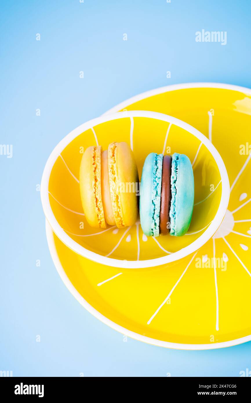 Macarons bleus et jaunes ou macarons sur une assiette jaune et un fond bleu Banque D'Images