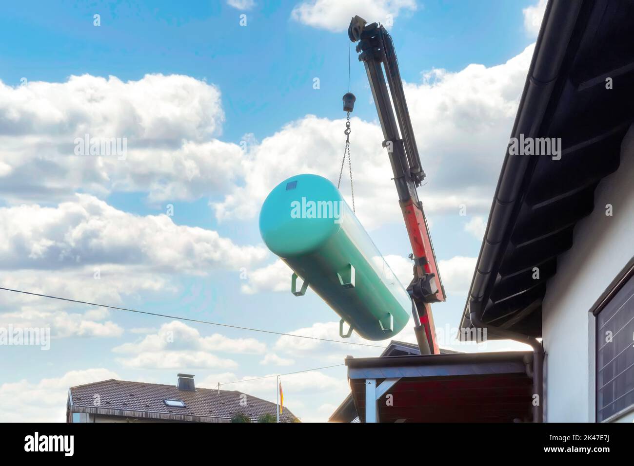 Livraison et installation d'un grand réservoir de gaz liquide dans le jardin d'une zone résidentielle. La grue soulève le réservoir dans le jardin Banque D'Images