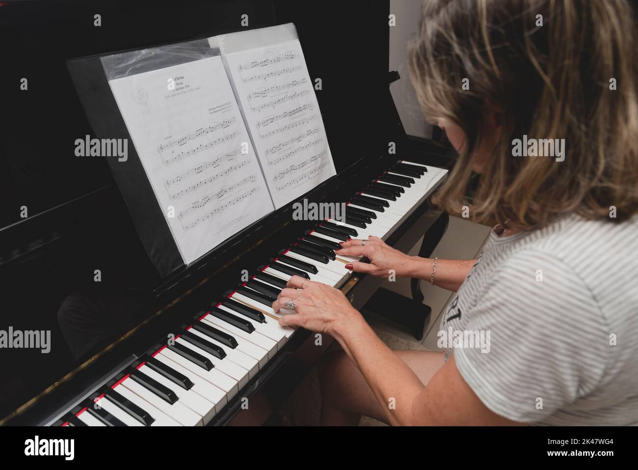 Belle pianiste brésilienne femme touchant les touches du piano, jouant du piano droit. Concept d'enseignement de la musique et des arts détendez-vous et joyeux. Banque D'Images