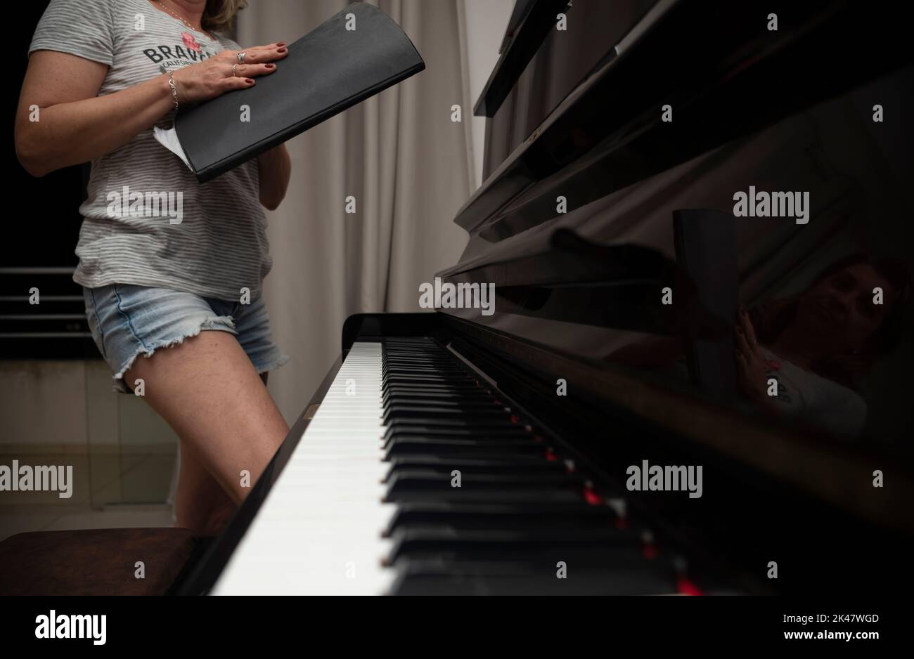 Femme se préparant à jouer du piano droit. Concept d'enseignement de la musique et des arts détendez-vous et joyeux. Banque D'Images