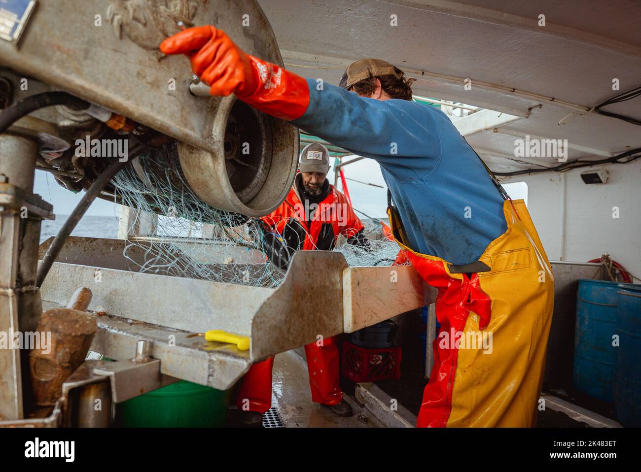 27 septembre 2022, Portland, Maine, États-Unis : un membre d'équipage à bord d'un bateau de pêche commercial lance le levier d'une machine qui transporte des filets de pêche hors de la mer tandis qu'un autre membre d'équipage démêle les poissons des filets au large de la côte du Maine. A bord d'un bateau de pêche au filet maillant, l'équipage porte ses prises de lotte, de goberge et de morue du début de la matinée jusqu'à tard dans la nuit. L'industrie de la pêche dans le Maine a récemment pris un coup avec un nouvel ensemble de restrictions sur la pêche et l'organisation environnementale Seafood Watch recommandant aux gens d'éviter de manger du homard américain. Ce listi Banque D'Images