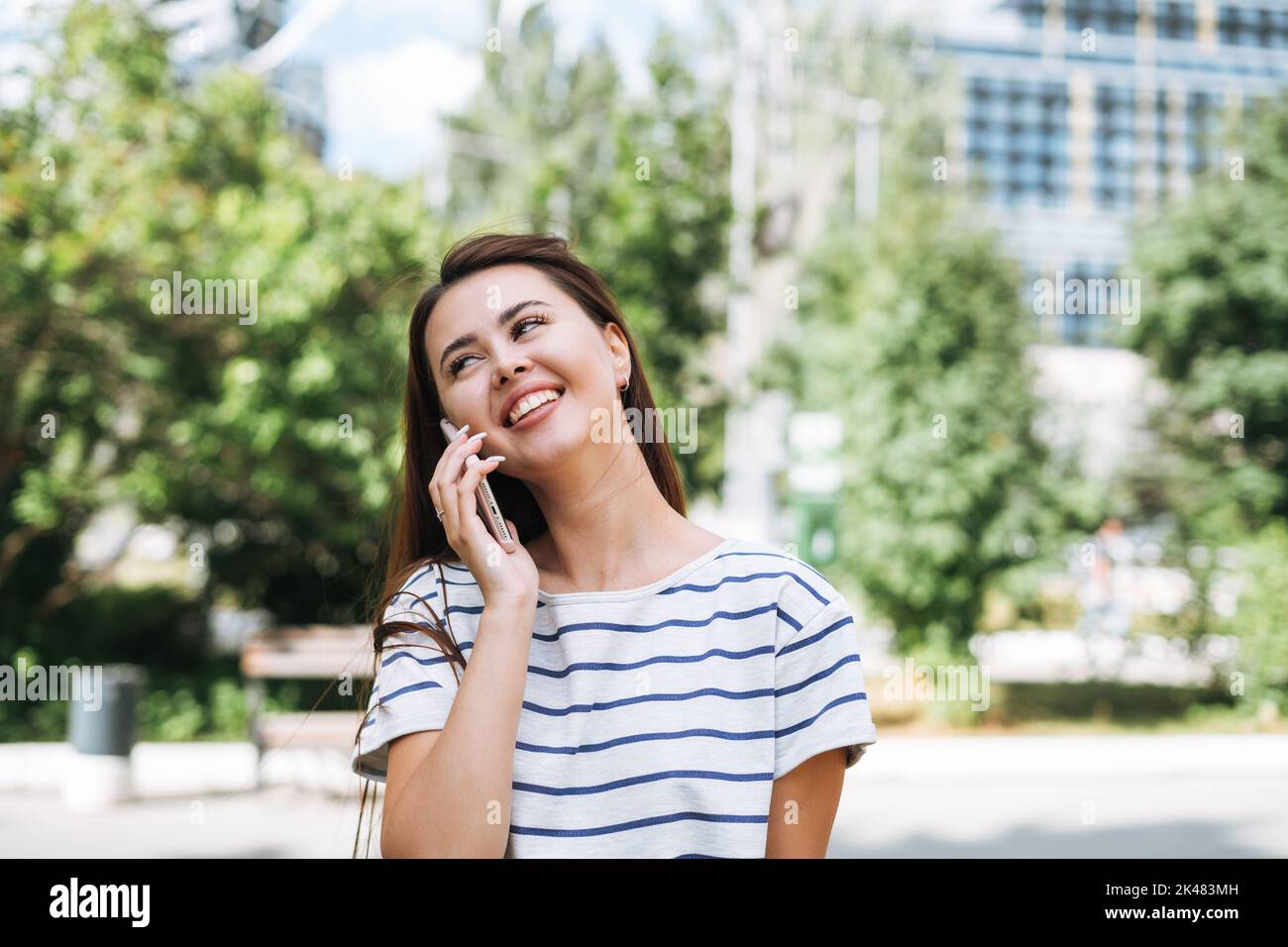 Portrait d'une jeune femme étudiante avec de longs cheveux à l'aide d'un téléphone portable dans le parc de la ville Banque D'Images