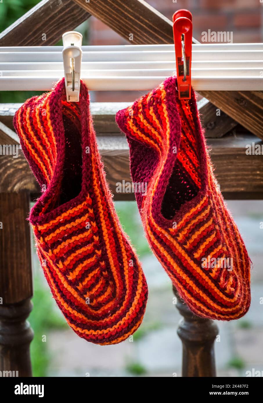 Des chaussons tricotés orange sèchent dans l'arrière-cour. Banque D'Images