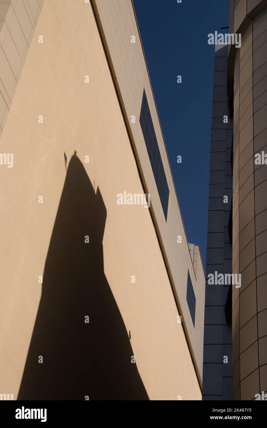 Photographie architecturale de deux grands bâtiments de ville crème avec fenêtres en verre, ombre et fond bleu ciel. Banque D'Images