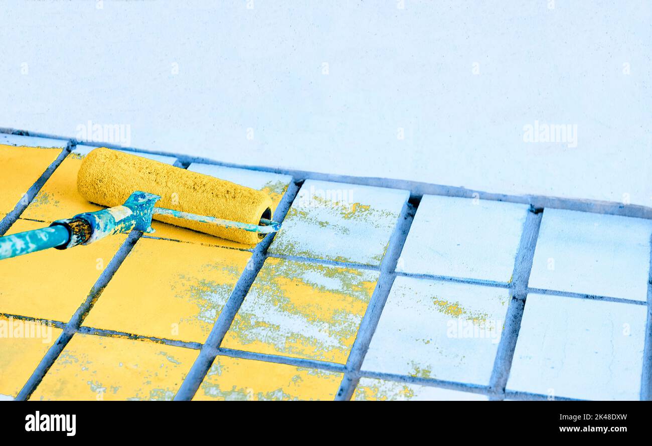 Rouleau de peinture sur la surface murale bleue avec de la peinture jaune Banque D'Images Rouleau de peinture sur la surface murale bleue avec de la peinture jaune Banque D'Images