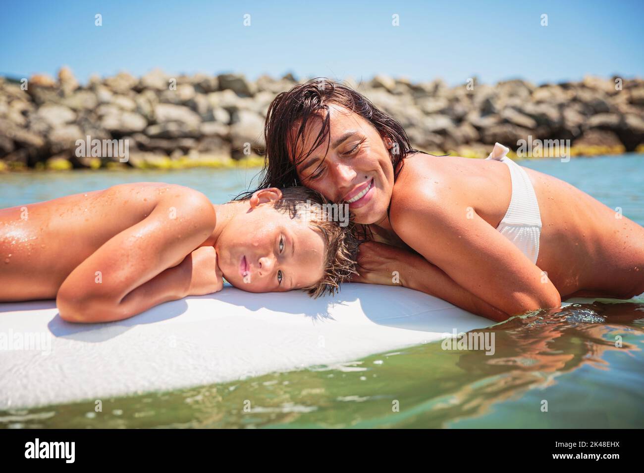 Maman avec son fils adolescent allongé sur une planche à natation Banque D'Images