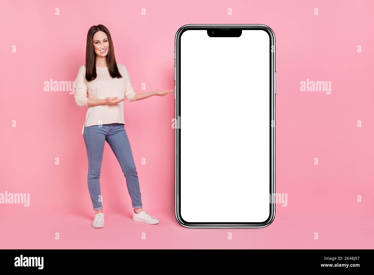 Photo de la fille vendeur présentant grand grand téléphone cellulaire écran tactile nouveau design panneau d'interface isolé couleur rose fond Banque D'Images
