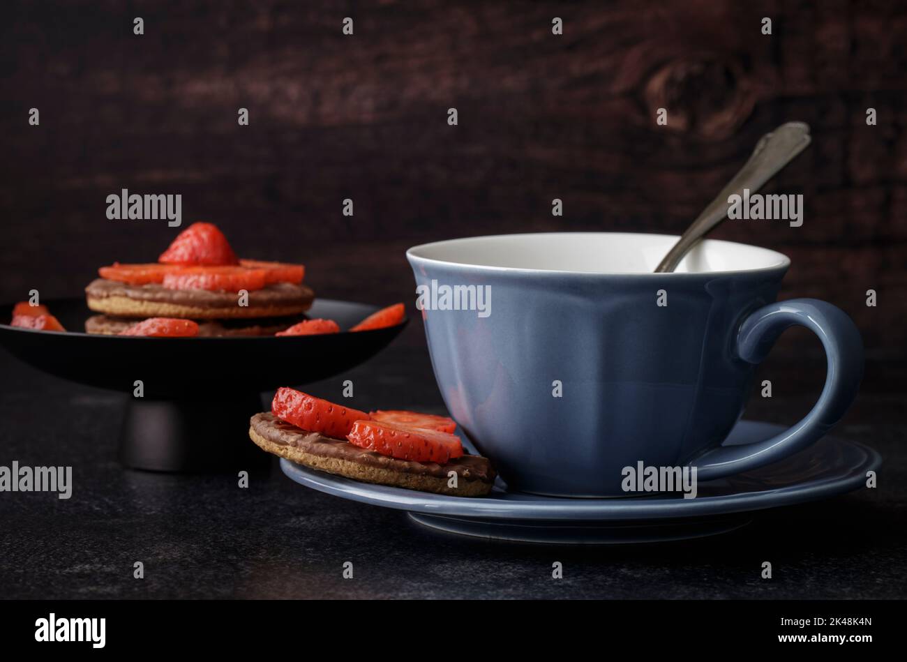 Tasse et soucoupe bleues avec biscuits au chocolat et fraises Banque D'Images