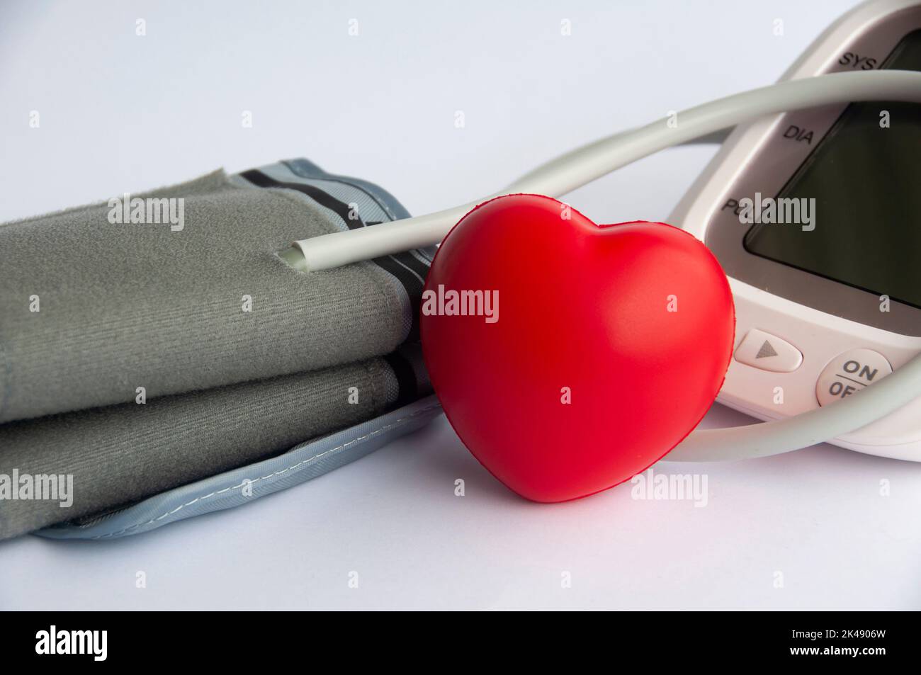 Moniteur numérique de tension artérielle et forme du cœur sur fond blanc. Banque D'Images