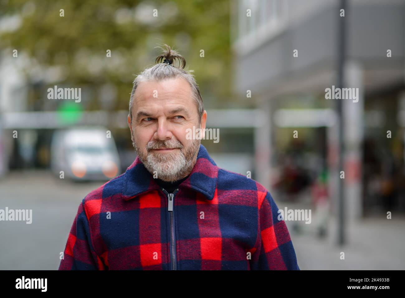 Un homme d'âge moyen avec un petit pain désordonné dans une veste rouge et  bleue de style bûcherons avec un regard espiègle sur le côté dans une rue  commerçante Photo Stock -