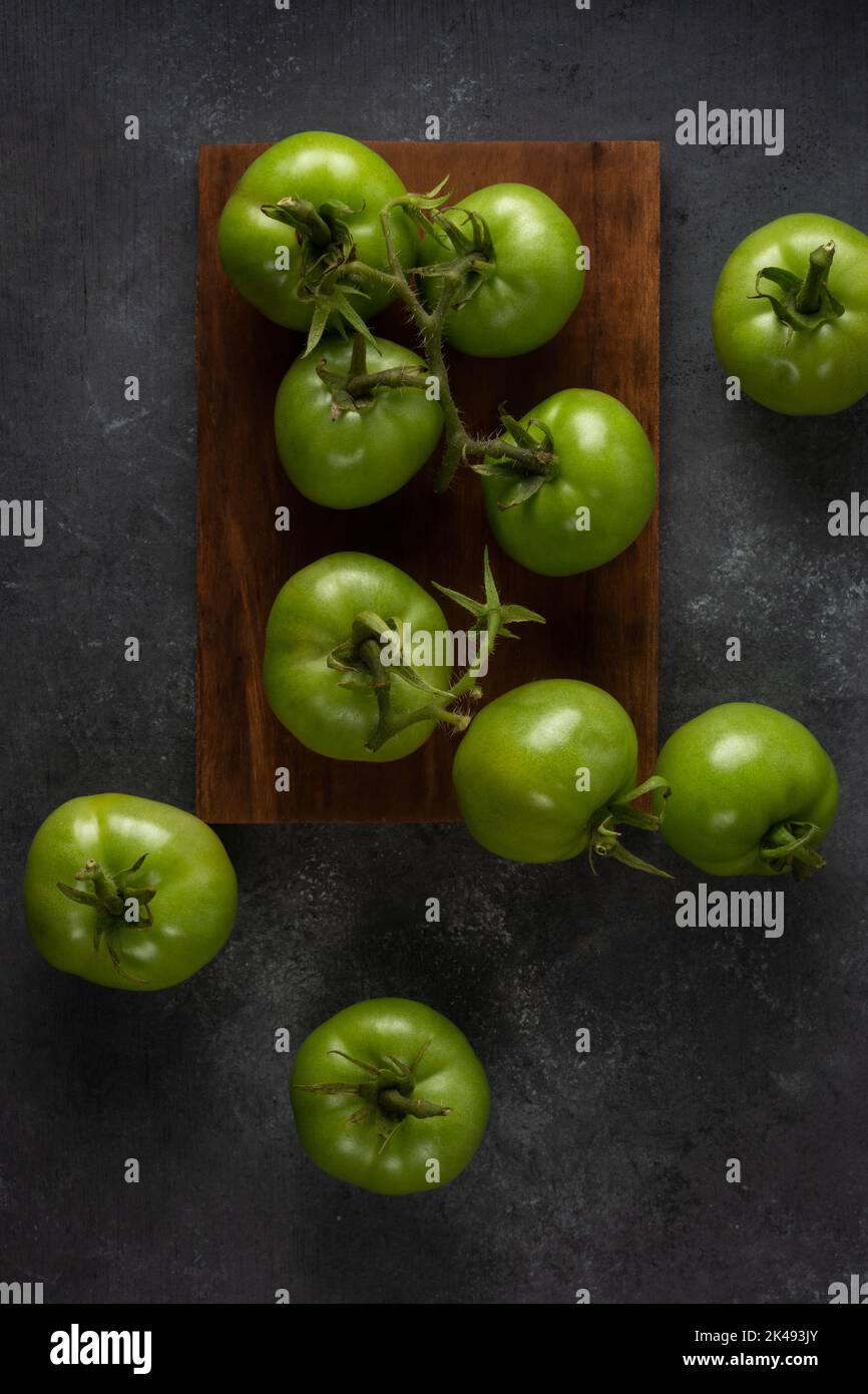 tomates éparses, baies vertes fraîchement récoltées sur une surface de table noire texturée, prises d'en haut Banque D'Images