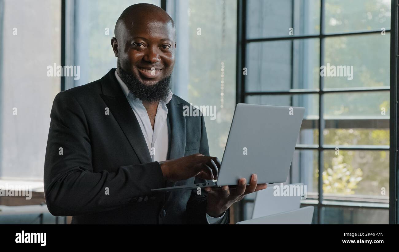 Homme d'affaires américain africain entrepreneur pdg analyste investisseur stand dans moderne skyscraper bureau tenir le travail d'ordinateur portable dans le département de marketing e-commerce Banque D'Images