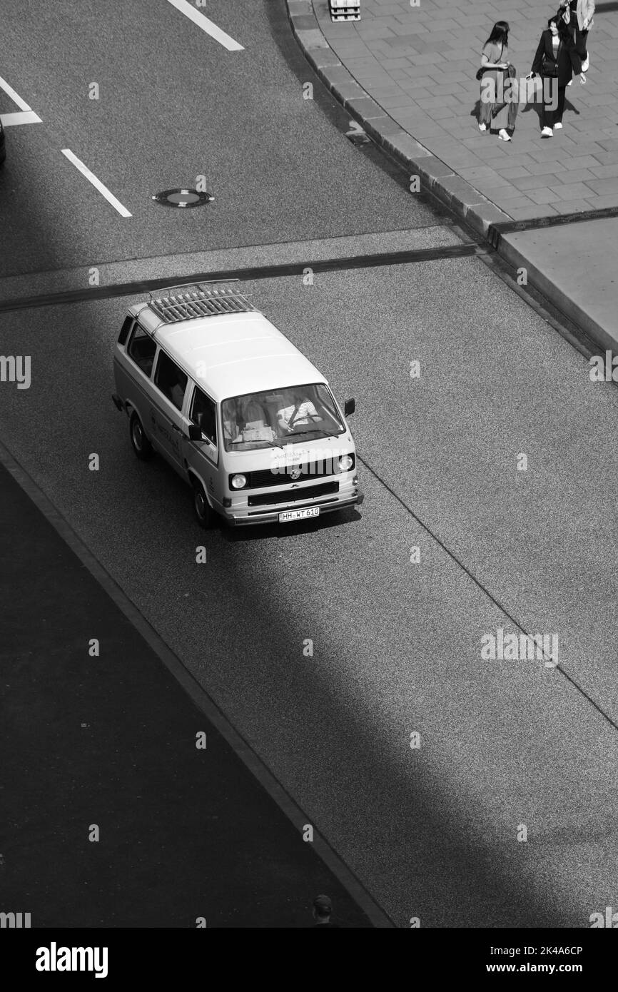 Un cliché vertical noir et blanc d'un Volkswagen Bulli sur une route vide Banque D'Images