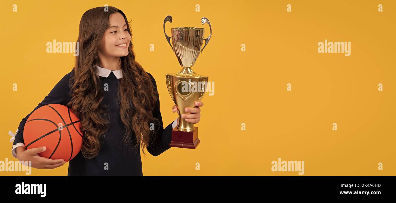 prix d'excellence sportive. jeune fille avec ballon de basket-ball et coupe de champion. Affiche horizontale de visage enfant isolé, en-tête de bannière, espace de copie. Banque D'Images