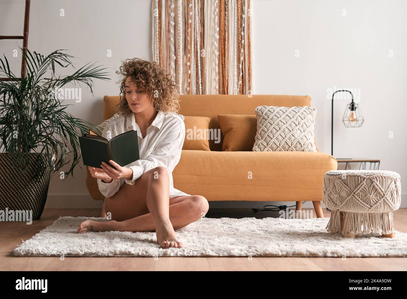 Femme pensive lisant le livre le week-end à la maison Banque D'Images