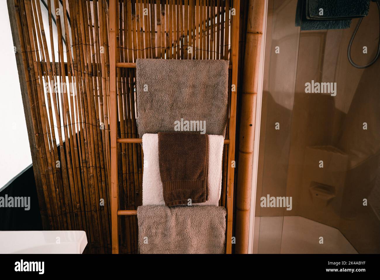 serviettes propres et douces disposées sur les marches de l'échelle en bois à côté du mur des cannes en bambou dans une salle de bains propre dans la tente Banque D'Images