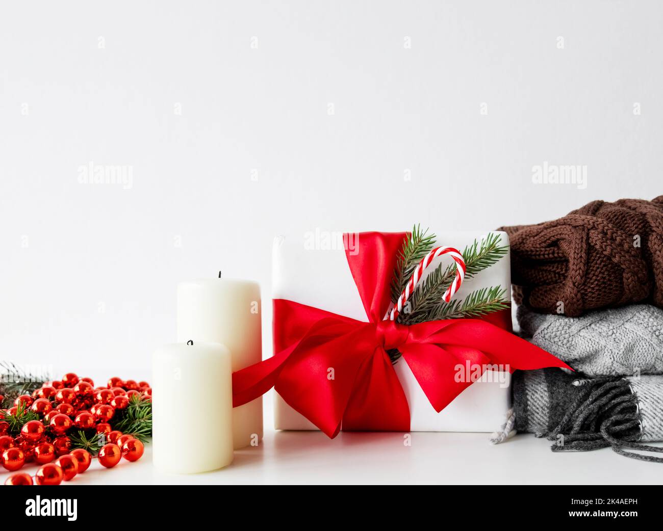 Textile de Noël. Hygge d'hiver. Décoration de fête. Réduction vacances. Boîte cadeau avec noeud en ruban rouge chaud pull chandail carreaux bougie ensemble isolé Banque D'Images