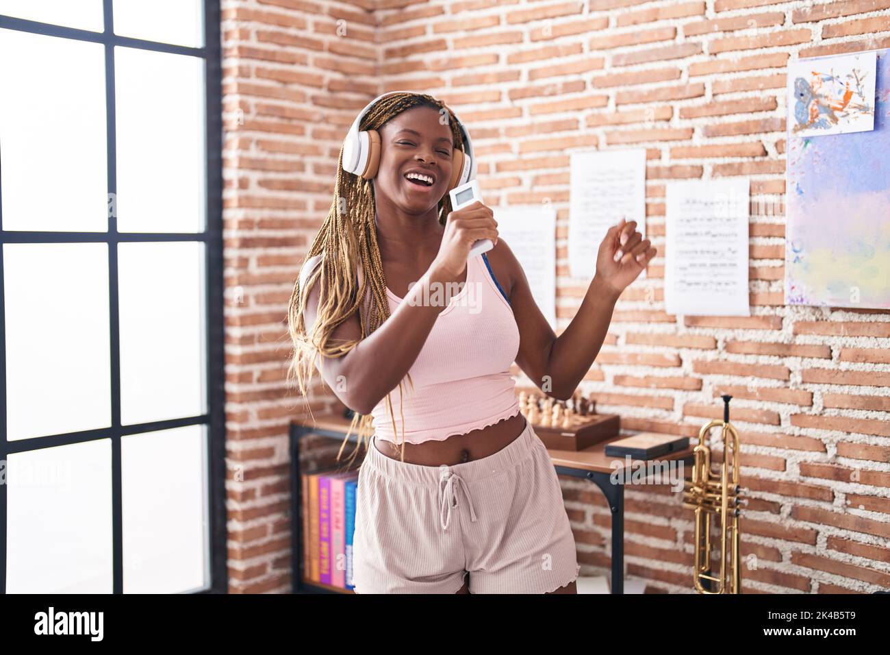 Femme afro-américaine écoutant de la musique chantant à la maison Banque D'Images
