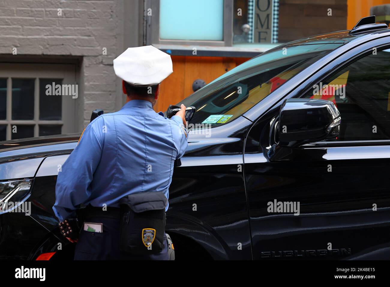 Un agent d'application de la réglementation NYC Traffic analyse l'enregistrement d'un véhicule à moteur à l'aide d'un appareil sans fil portatif offrant un accès en temps réel à l'information sur les billets de stationnement Banque D'Images