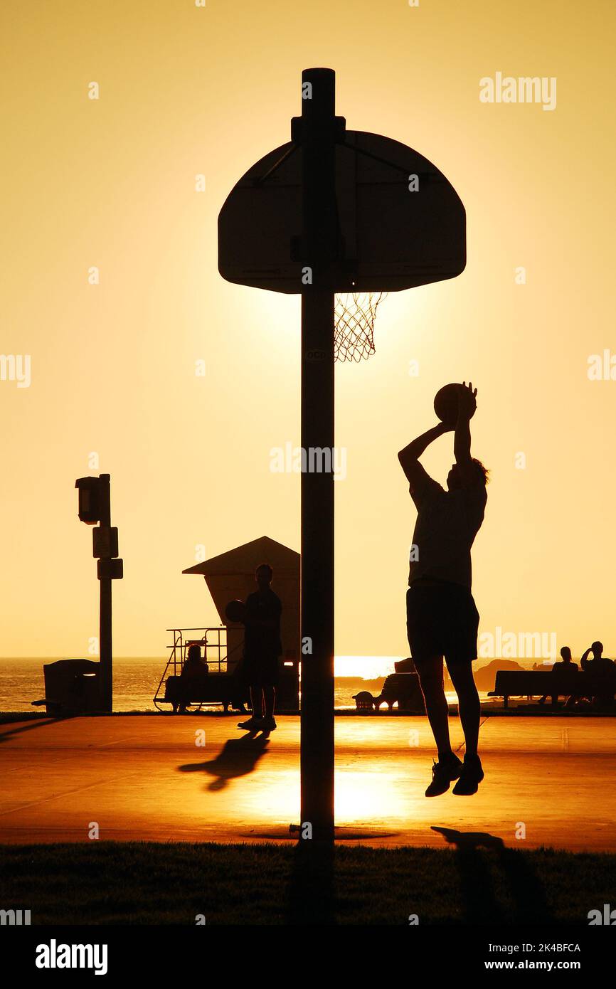 Un homme adulte prend une mise en plan sur un terrain de basket-ball extérieur pendant que le soleil se couche Banque D'Images