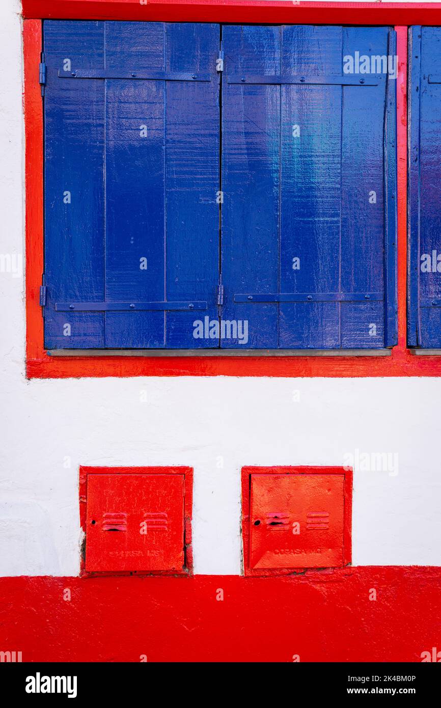 Fenêtre avec panneaux de bois peints en bleu cobalt et garniture rouge à Sabará, Minas Gerais, Brésil Banque D'Images