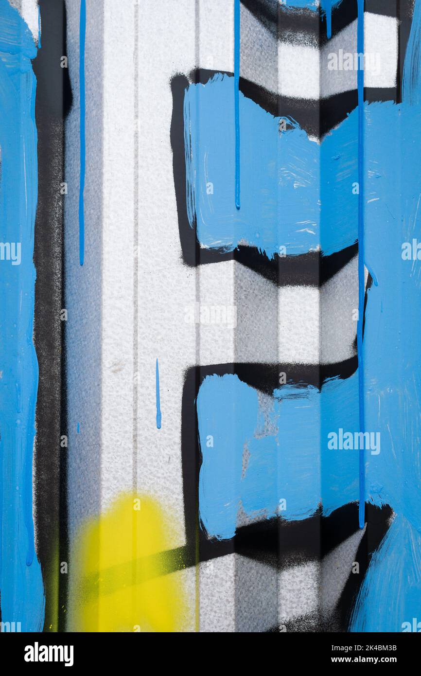 Lettre E blanche en majuscules peinte sur un mur en métal ondulé avec fond bleu. Banque D'Images