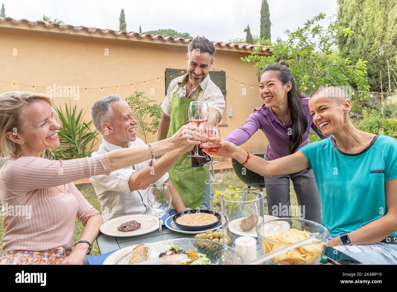 Des amis heureux en dégustant avec un grand sourire autour de la table dans le patio de la maison. Banque D'Images