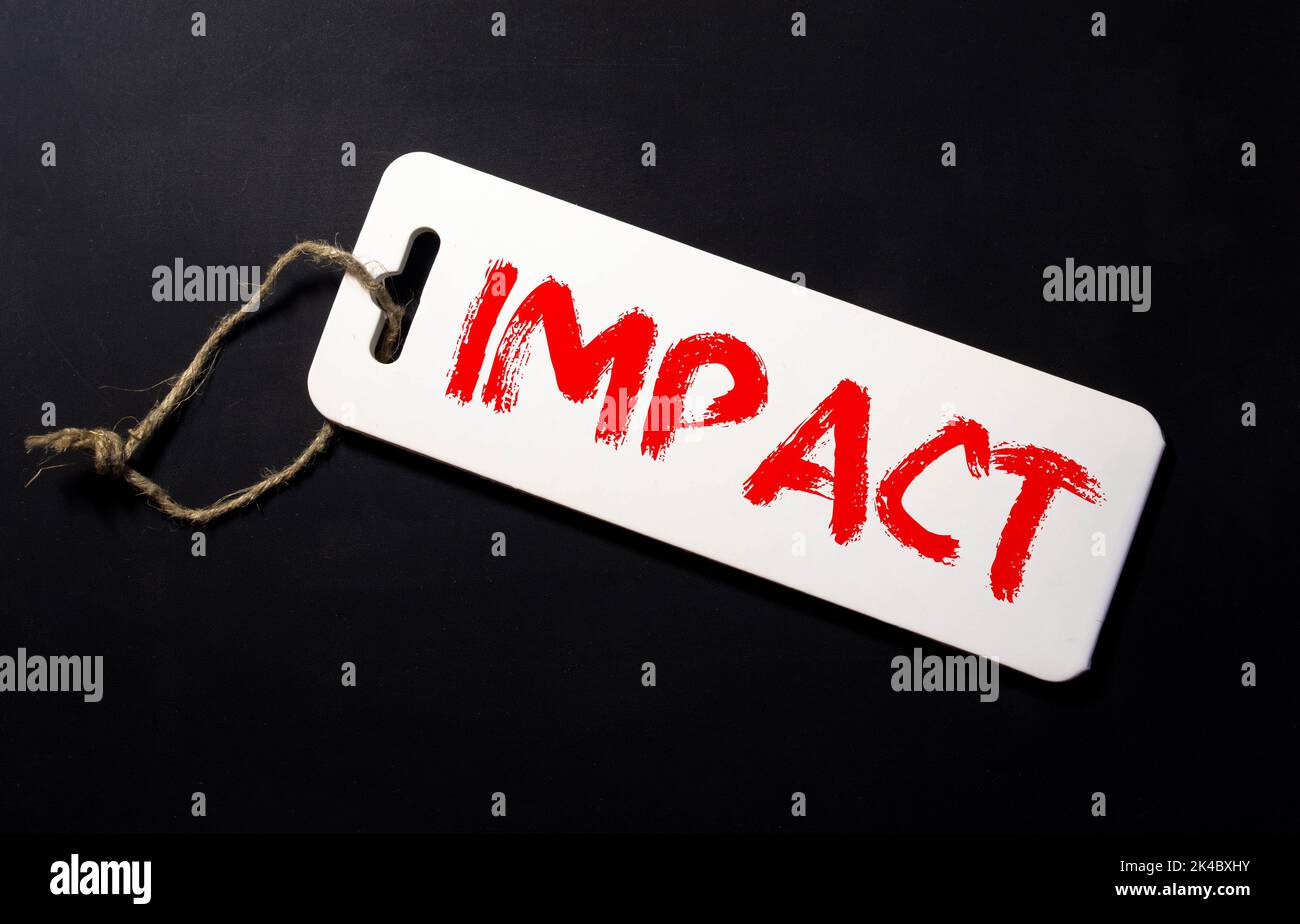 mot d'impact écrit sur fond gris avec des crayons et des trombones. Banque D'Images