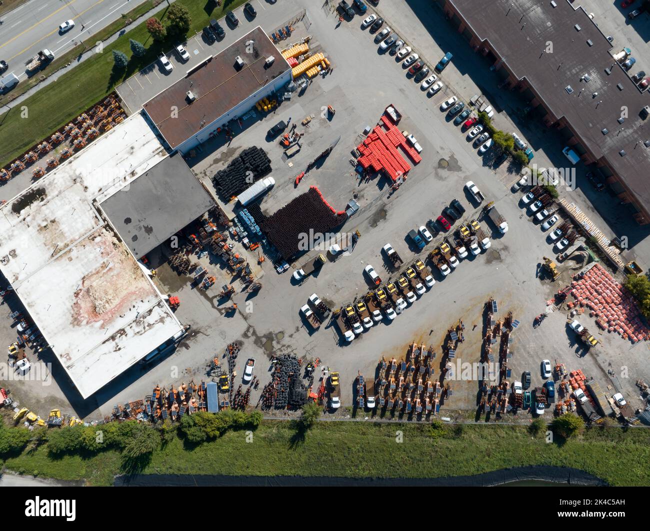 Une vue aérienne de haut en bas au-dessus d'un centre avec des fournitures de construction de routes, y compris des cônes de signalisation, des panneaux, des machines et plus encore. Banque D'Images