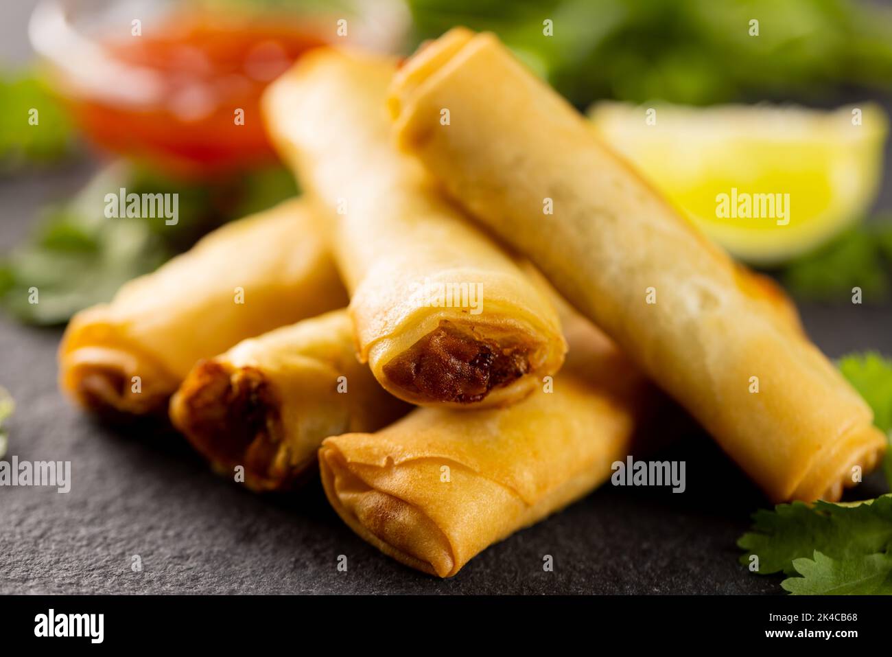 Gros plan sur des rouleaux de printemps asiatiques, des tranches de citron vert et de sauce Chili sur fond gris Banque D'Images