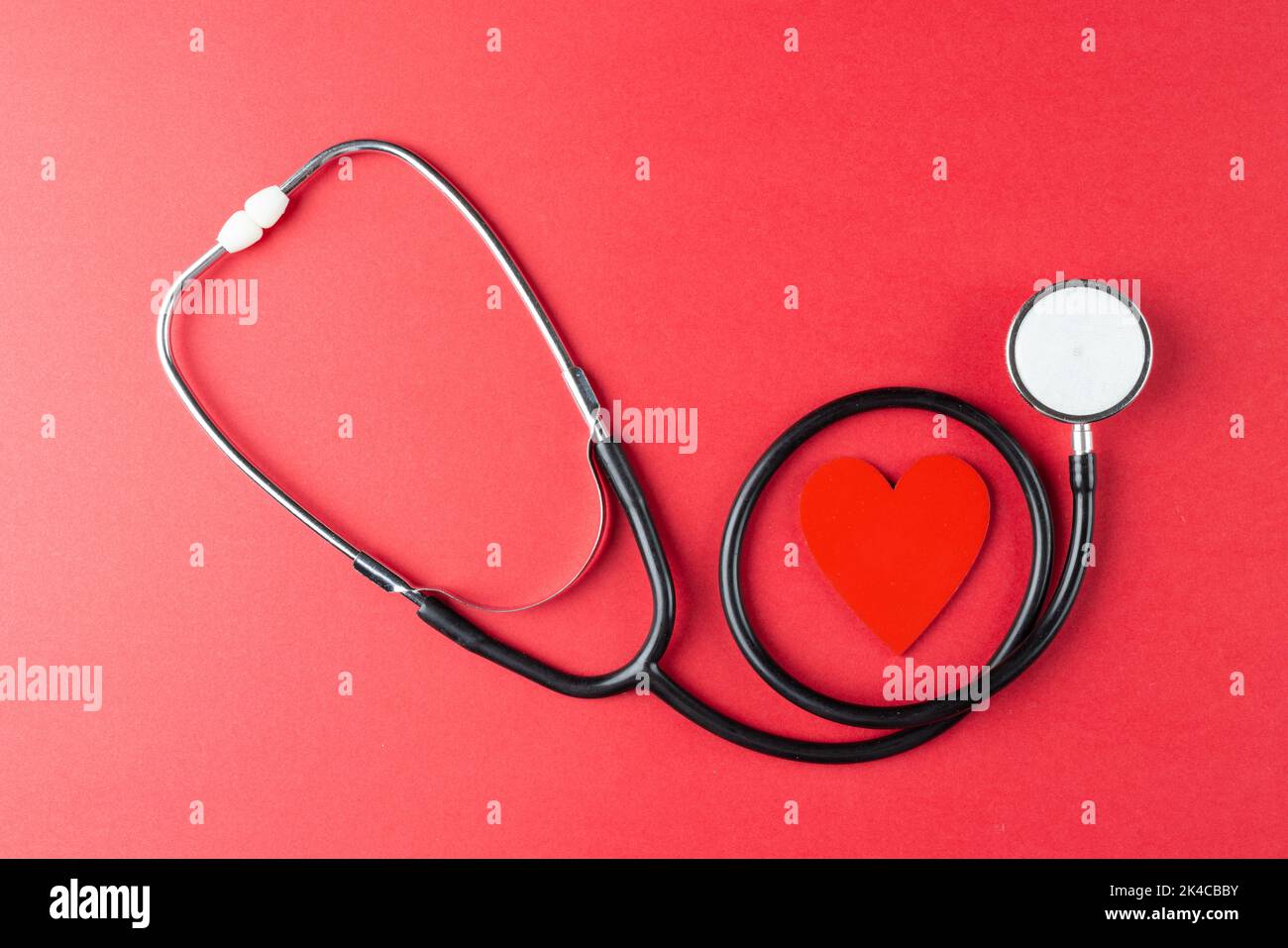 Image du cœur rouge et du stéthoscope sur la surface rouge Banque D'Images