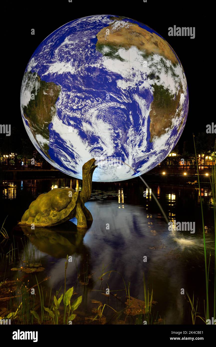Une fontaine de sculpture d'une tortue géante avec un grand hologramme de la planète Terre en arrière-plan Banque D'Images