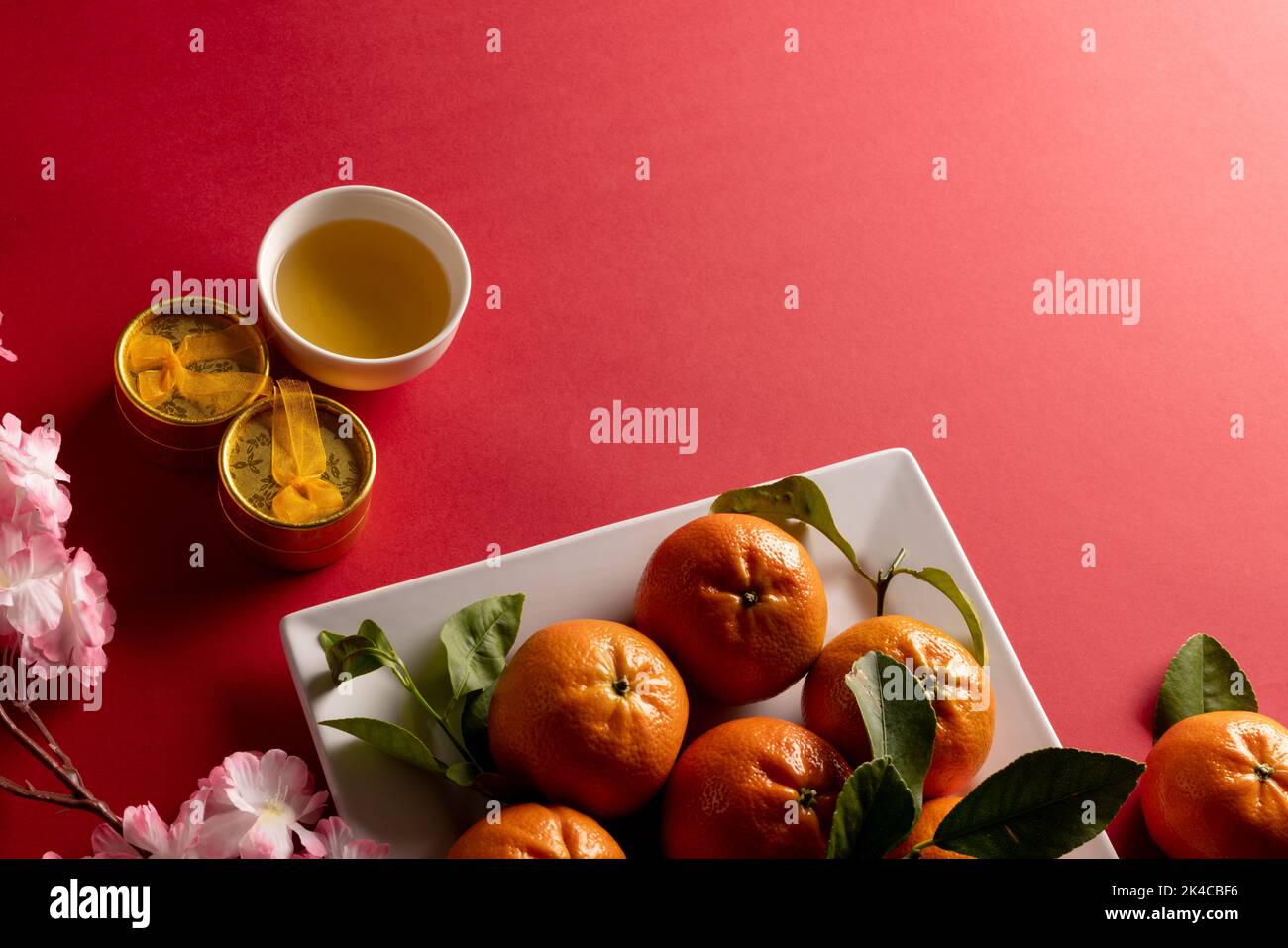 Composition de gros plan de cerisiers en fleurs et d'oranges sur fond rouge Banque D'Images