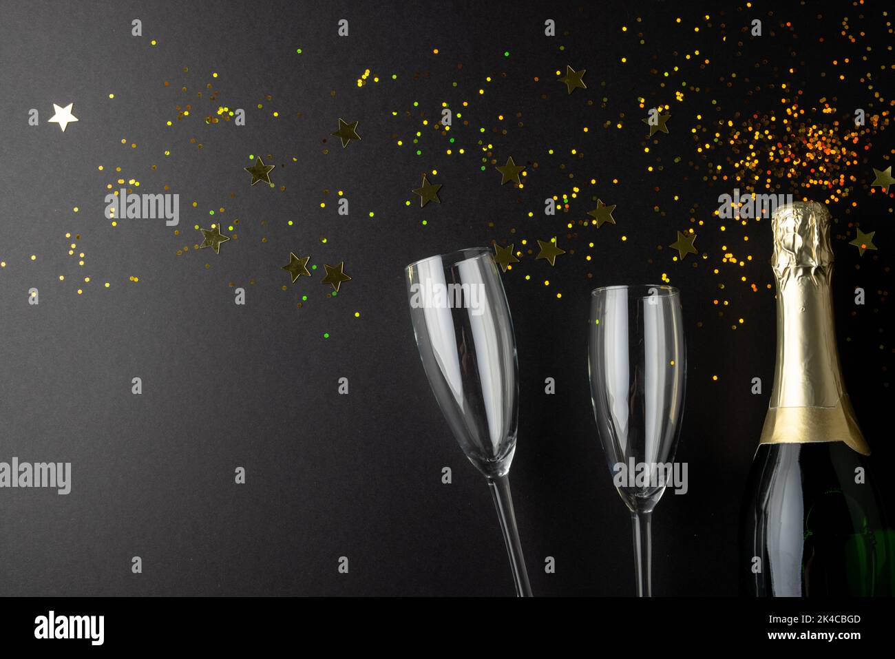 Composition de gros plan de champagne du nouvel an et confetti sur fond noir Banque D'Images