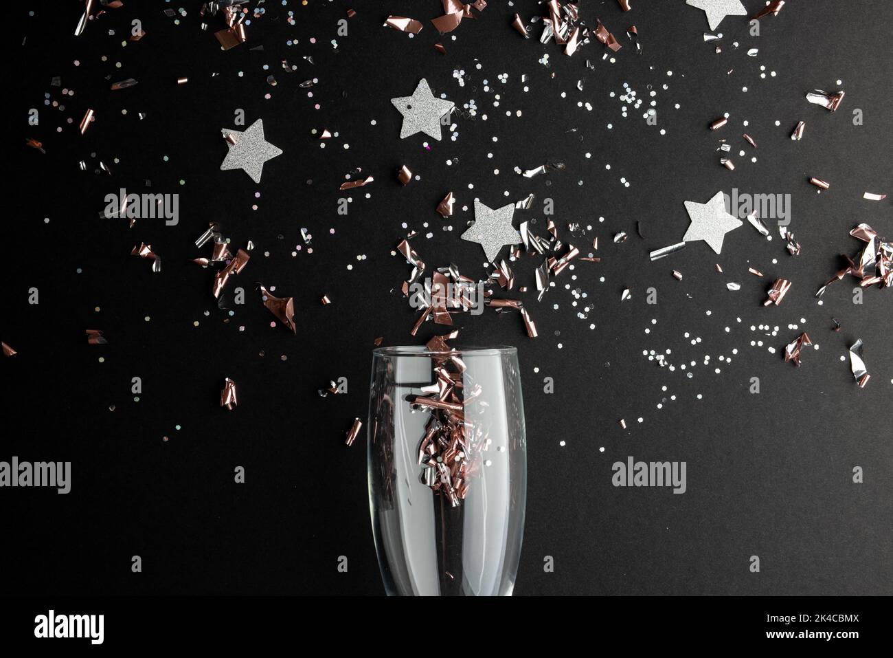 Composition de gros plan de champagne du nouvel an et confetti sur fond noir Banque D'Images