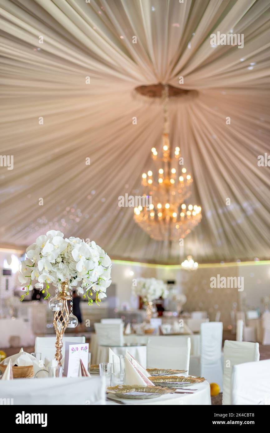 La vue verticale d'un lustre donnant d'un plafond beige de tente de mariage  sur le mobilier décoré Photo Stock - Alamy