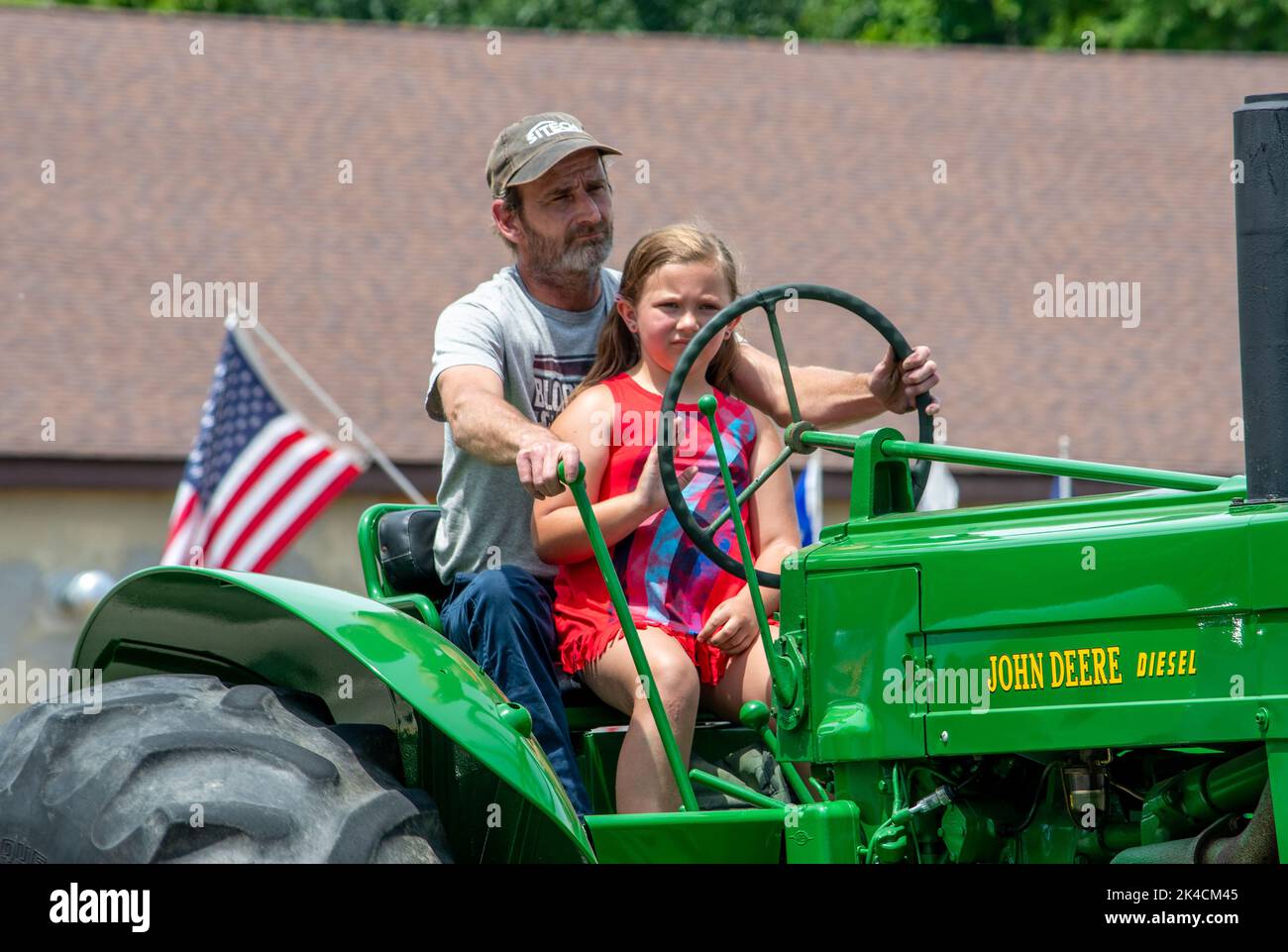Eau Claire MI USA, 4 juillet 2022; jeune fille roule sur un tracteur avec papa, dans une parade le 4th juillet Banque D'Images