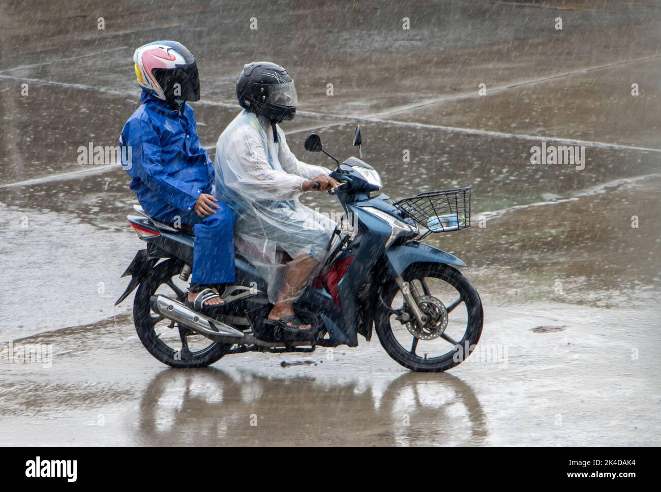 Mototaxi conduit avec un passager sous une forte pluie Banque D'Images