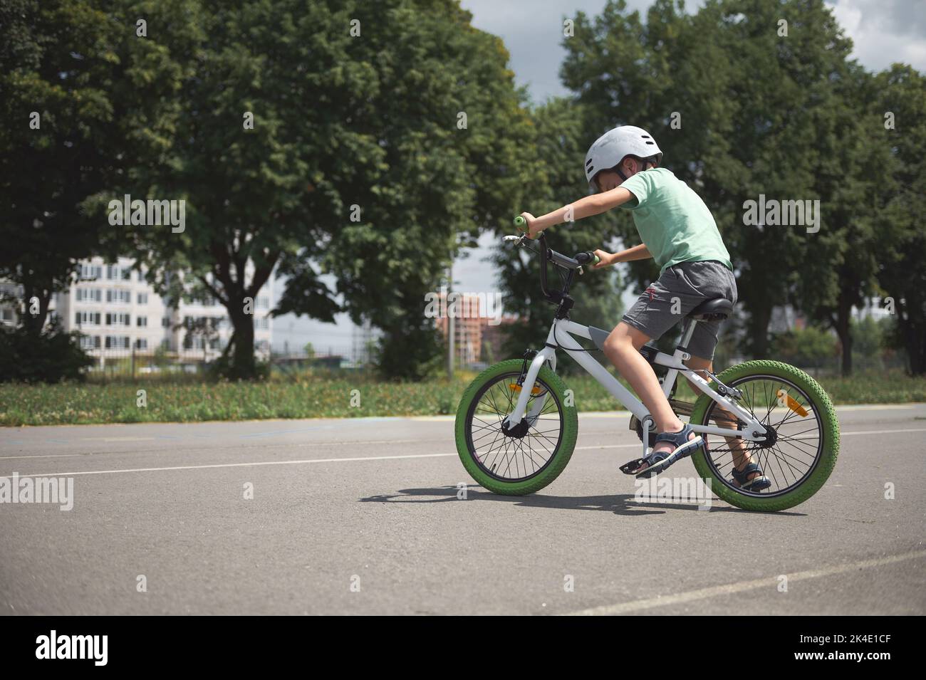 Un garçon d'âge scolaire apprend les tours extrêmes et le vélo extrême dans la ville. Enfant sportif dans un équipement de protection à vélo Banque D'Images