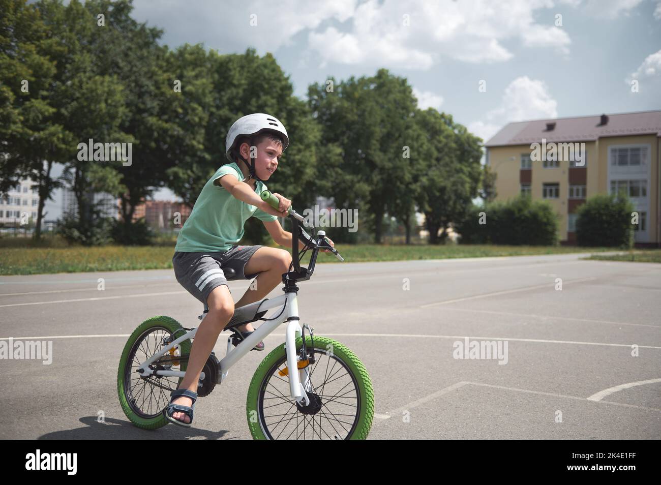 Garçon sportif actif dans un casque de sport en toute confiance, à vélo. L'enfant d'âge scolaire caucasien fait du vélo sur la route asphaltée de la ville Banque D'Images