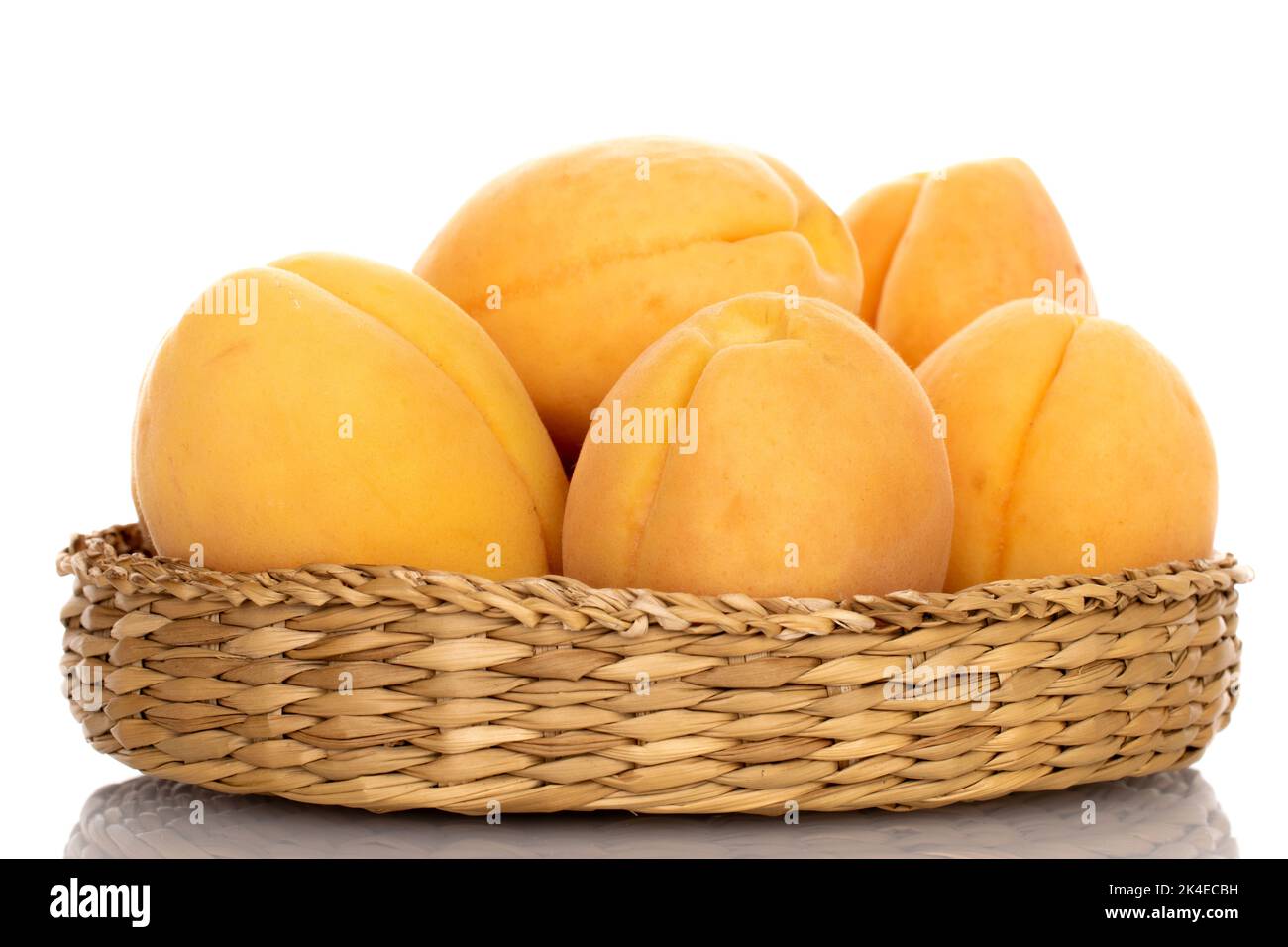 Plusieurs abricots mûrs d'ananas dans une plaque de paille, en gros plan, isolés sur du blanc. Banque D'Images