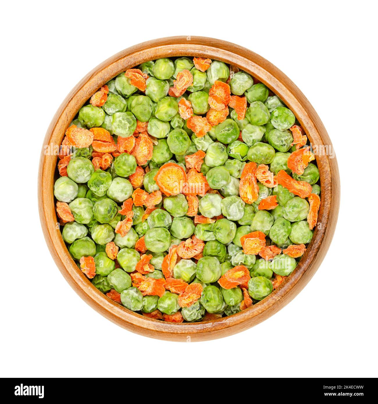 Pois verts déshydratés et morceaux de carottes dans un bol en bois. Légumes mélangés. Graines de fruits à gousse Pisum sativum, et carottes d'orange coupées, Daucus carota. Banque D'Images