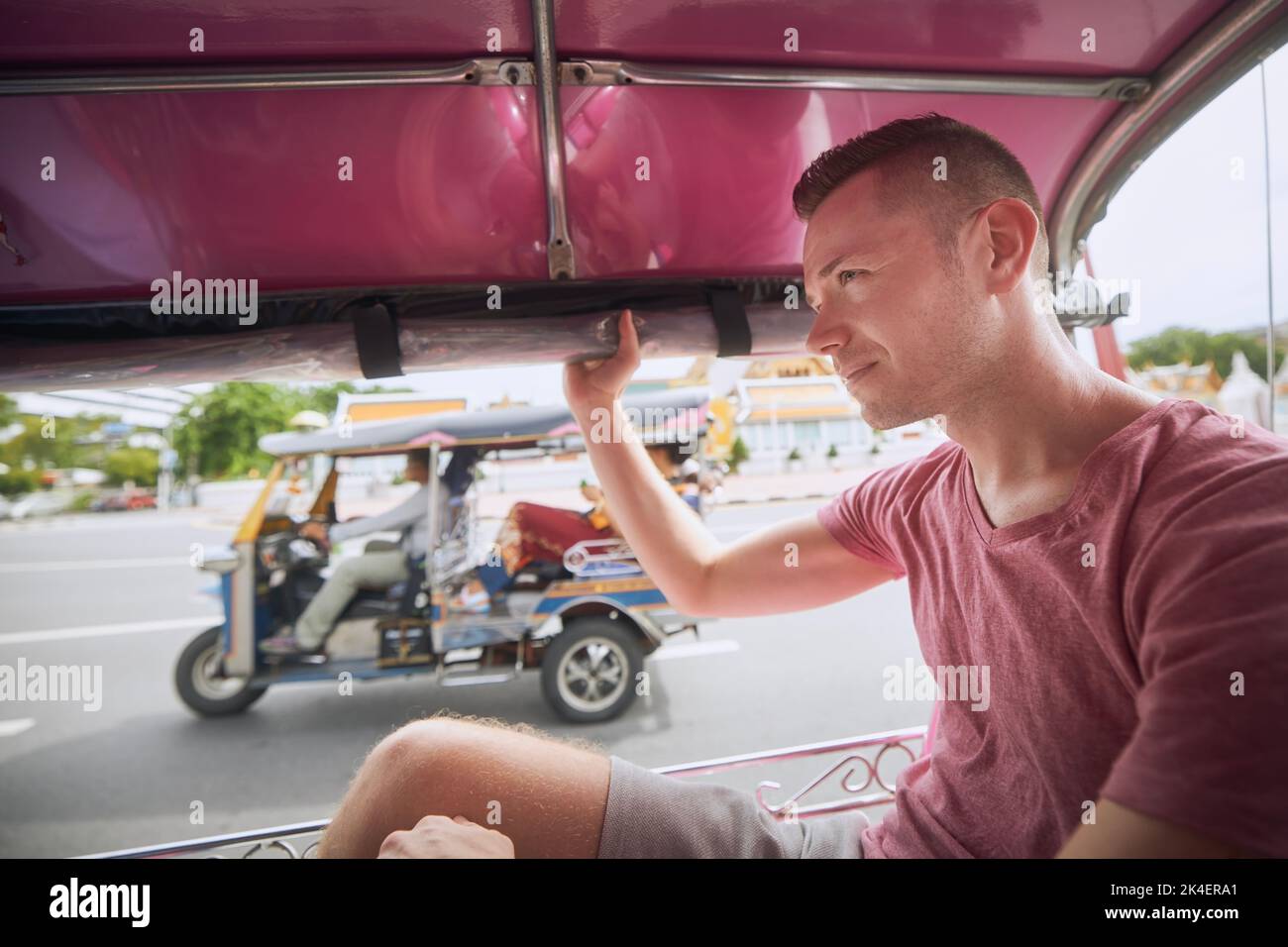 Homme profitant d'une promenade en tuk tuk pendant la journée ensoleillée. Portrait du touriste en taxi. Bagkok, Thaïlande Banque D'Images