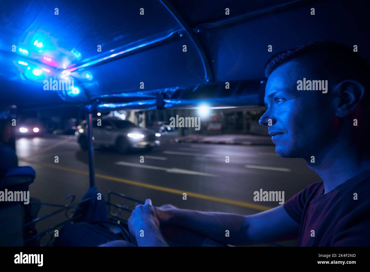 Homme en train de profiter d'une promenade en tuk tuk la nuit. Portrait du touriste en taxi. Bangkok, Thaïlande Banque D'Images