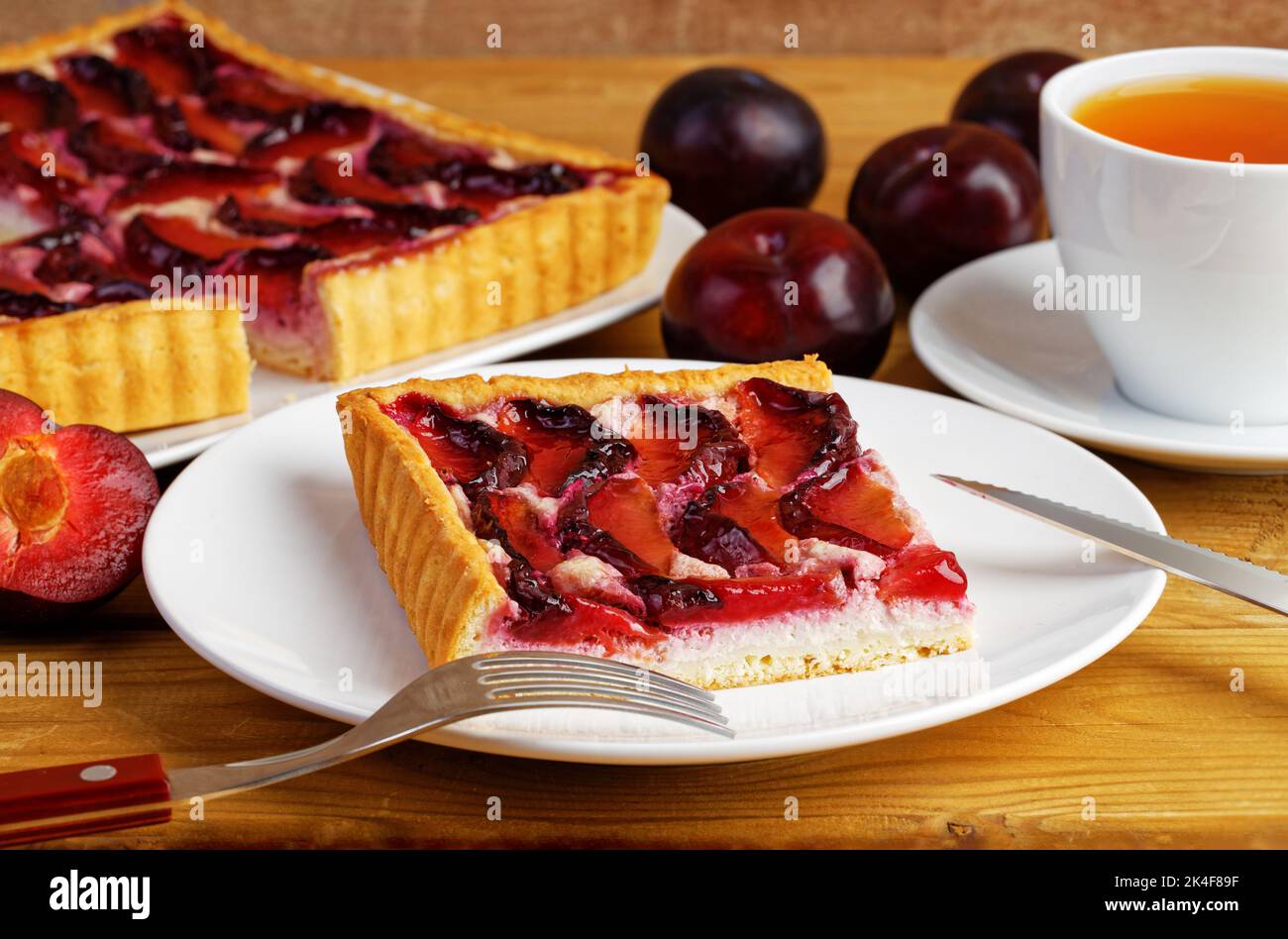 Gâteau aux prunes maison et tasse de thé sur table en bois. Mise au point peu profonde. Banque D'Images Gâteau aux prunes maison et tasse de thé sur table en bois. Mise au point peu profonde. Banque D'Images
